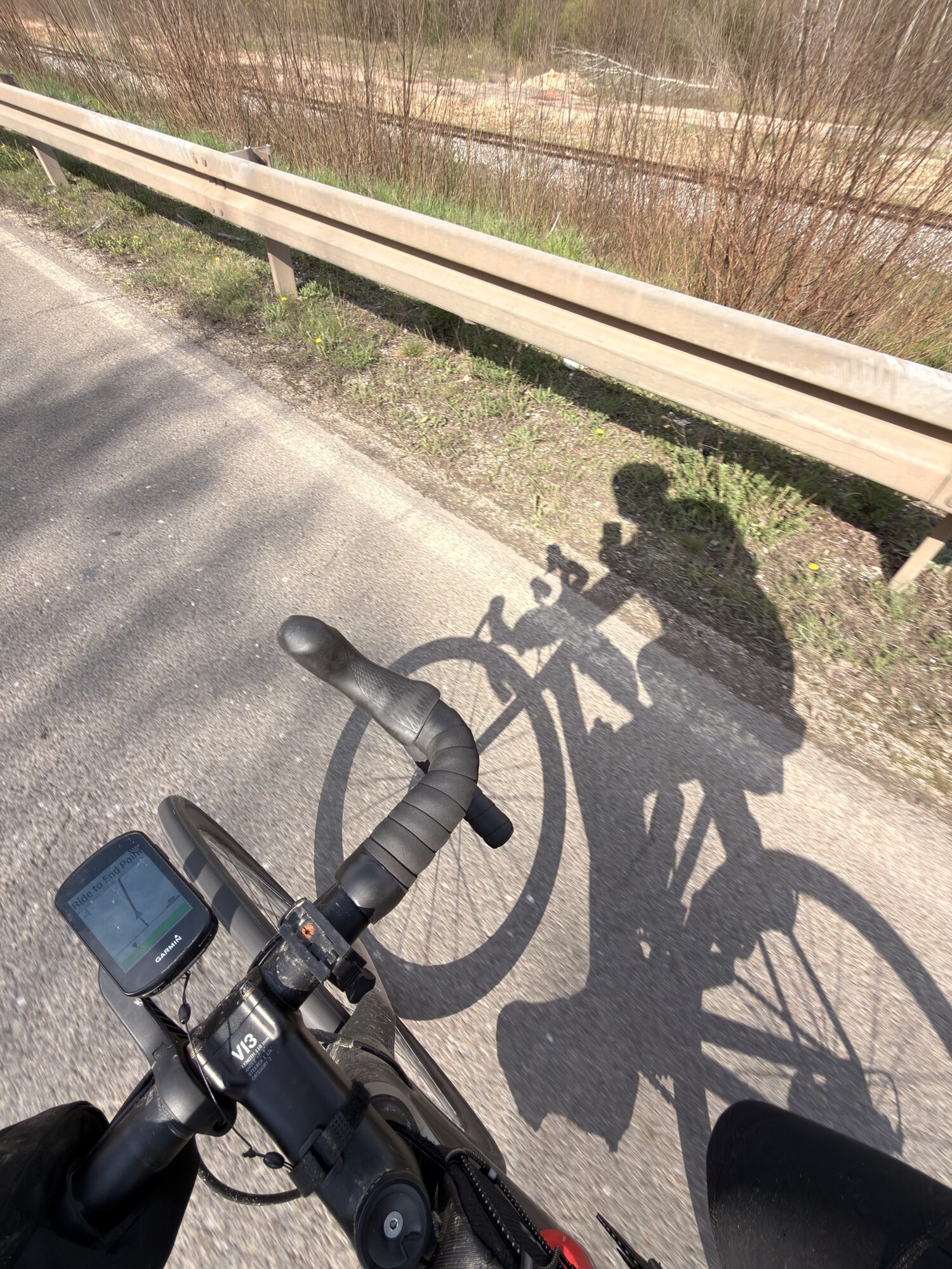 Pogled sa bicikla na Garmin računar i senku bicikliste na asfaltu.